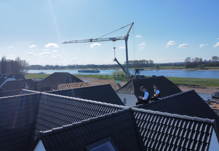 Zu sehen sind die Inhaber von Firstetage Leverkusen, Felix Issinger und Leon Hienert sitzend auf dem Dach eines Hauses.